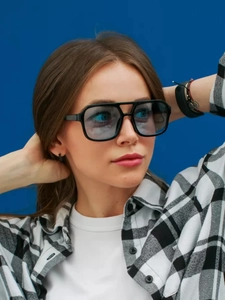 Fashionable pilot sunglasses with blue lenses worn by a model against a blue background