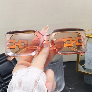 Detailed view of translucent amber rectangular sunglasses with geometric chain temples