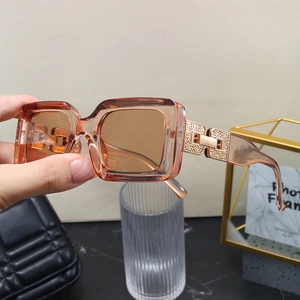 Detailed macro view of the golden geometric embossed metal hinges on amber square sunglasses