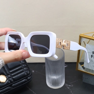 Detail of white thick-frame sunglasses with embossed gold metal hinge and grey lenses