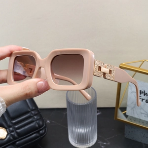 Close-up of rectangle sunglasses with nude frame and gold geometric hinge details