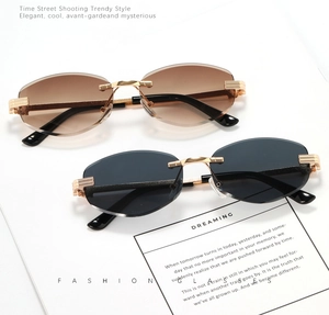 Detail view of gold metal sunglasses with brown and dark grey lenses on white paper
