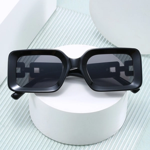 Modern black rectangle sunglasses with geometric hollow chain temples on a white stand