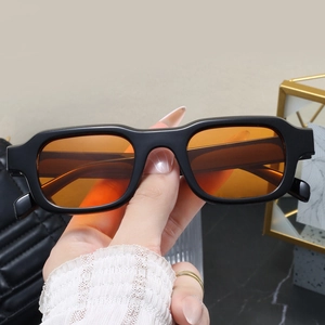Close-up of retro square sunglasses with thick black frames and orange tinted lenses