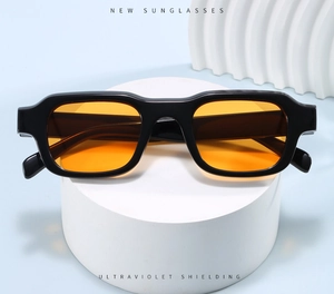 Detail of square vintage sunglasses with black thick frames and orange UV lenses