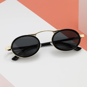 Retro steampunk sunglasses with oval black frames and gold metal accents on modern background