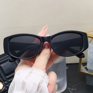 Detail shot of vintage black rectangular sunglasses held against a chic fashion backdrop