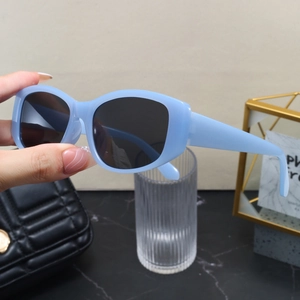 Detail of light blue rectangular sunglasses with dark lenses held against a modern backdrop