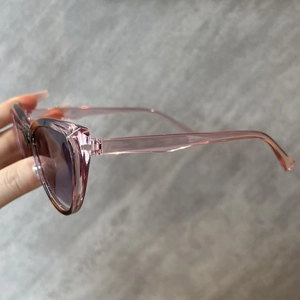 Seitenansicht der Vintage Cat-Eye Sonnenbrille mit pinken transparenten Rahmen und dunklen Gläsern