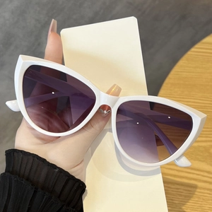Detailansicht der weißen Cat-Eye-Sonnenbrille mit Verlaufsgläsern vor Holzgrund