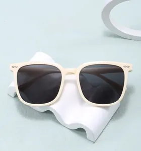 Creamy oversized sunglasses with metal arrow accents on a blue textured background