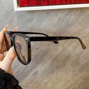 Detail view of bold black square frames featuring silver arrow metal accents on the temple
