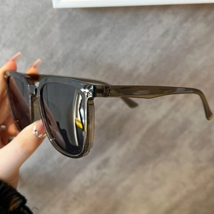 Detail of transparent grey frame sunglasses with silver arrow accents and grey lenses