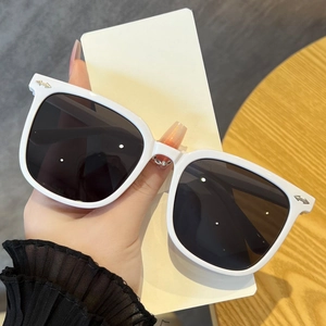 Detailed close-up of white oversized square sunglasses featuring silver arrow metal studs