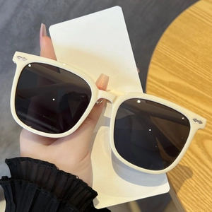 Detailed close-up of white oversized square sunglasses with silver arrow metal accents