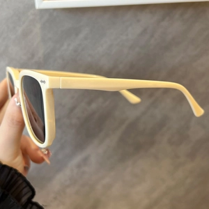 Close-up of cream sunglasses frame with silver arrow detail and thick temple design