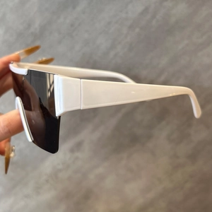 Détail de lunettes de soleil blanches sans monture avec larges branches et verre bouclier