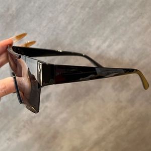 Gros plan sur des lunettes de soleil sans monture avec branches larges et verres noirs