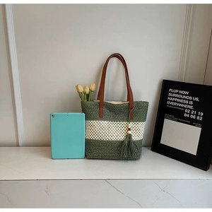 Detail of striped woven beach bag with green tassels and premium leather handles