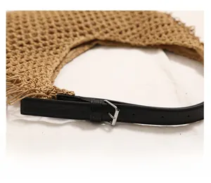 Detail of woven straw bag showing black leather strap with silver adjustable buckle