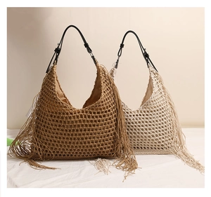 Detail of woven straw tote bag with fringe accents and adjustable black leather straps