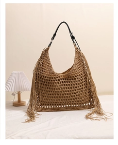 Detail of bohemian woven straw bag showing handmade hollow texture and long tassels
