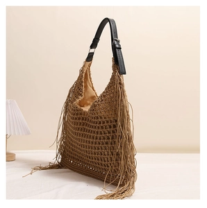 Detail of woven straw bag showing fringe accents and premium leather shoulder strap