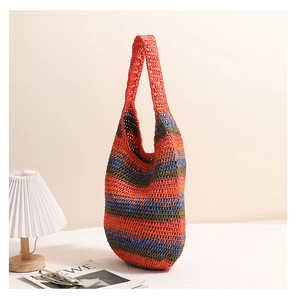 Close-up of vibrant orange and blue striped woven straw tote bag for beach vacations
