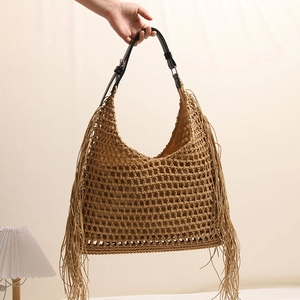 Straw shoulder bag with fringe tassels and black leather handles for beach vacation
