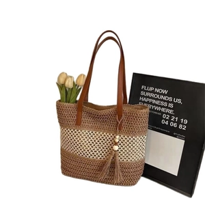 Handwoven straw tote bag with brown stripes, leather straps, and stylish fringe details