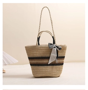 Détail du sac en paille avec rayures contrastées, doubles anses et foulard décoratif