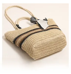 Détail du sac cabas en paille tissée avec motif à rayures et nœud décoratif pied-de-poule