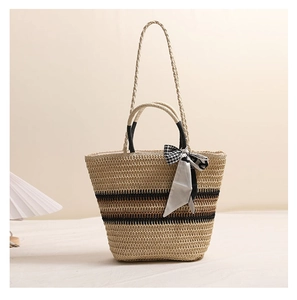 Détail d'un sac cabas en paille tissée avec rayures brunes et foulard en soie décoratif