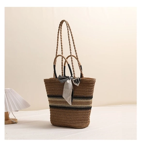 Vue détaillée du sac en paille tressée avec rayures noires et foulard en soie décoratif