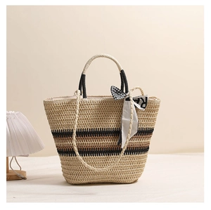 Détail du sac cabas en paille tressée avec motifs rayés et accessoire foulard en soie chic