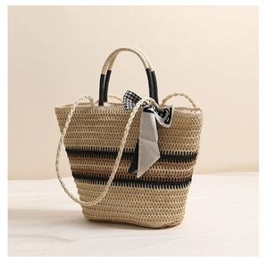 Détail d'un sac cabas en paille rayé avec un foulard en soie et texture tressée