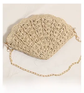 Close-up of shell-shaped straw bag featuring hollow crochet pattern and gold metal chain