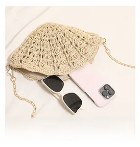 Detail view of woven straw crossbody bag showing capacity for phone and sunglasses