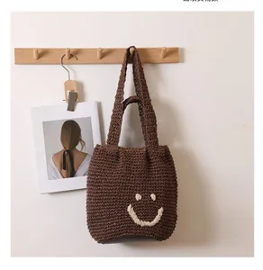 Detail of dark brown woven shoulder bag with a cream-white stitched smiley face icon