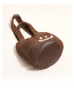 Detail view of the circular leather base and woven texture of the smiley face crochet bucket bag
