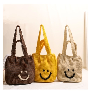 Close-up of three colorful woven cotton handbags with smiley face embroidery and texture