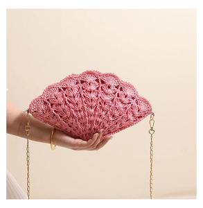 Detailed view of pink shell-shaped woven crossbody bag with elegant hollow knit texture