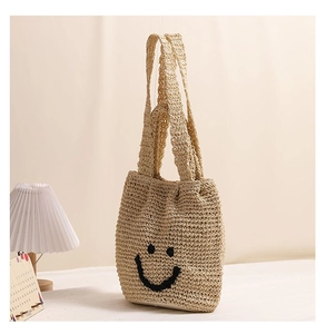 Close-up of a handwoven cotton tote bag featuring a black embroidered smiley face detail