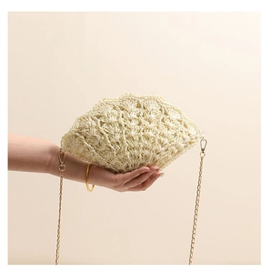 Detail of hand-held beige shell-shaped straw bag with intricate crochet wave textures