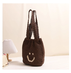 Close-up of hand-woven coffee brown tote bag with white smiley face embroidery detail