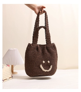 Detail of dark brown crochet shoulder bag with a white stitched smiley face design