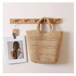 Detail of raffia handbag showing intricate hollow weave patterns and solid handles