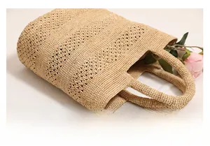 Detail of the geometric handle and intricate hollow weave of the raffia tote bag
