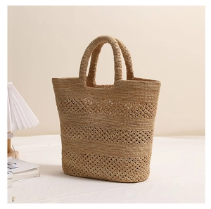 Detailed macro view of the handcrafted raffia tote bag with hollowed-out woven patterns