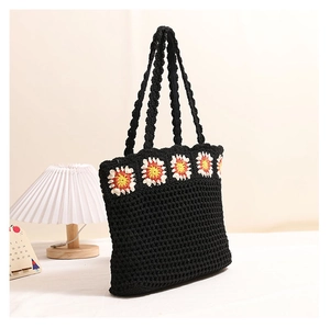 Détail d'un sac cabas en crochet noir avec des appliques de fleurs de marguerites